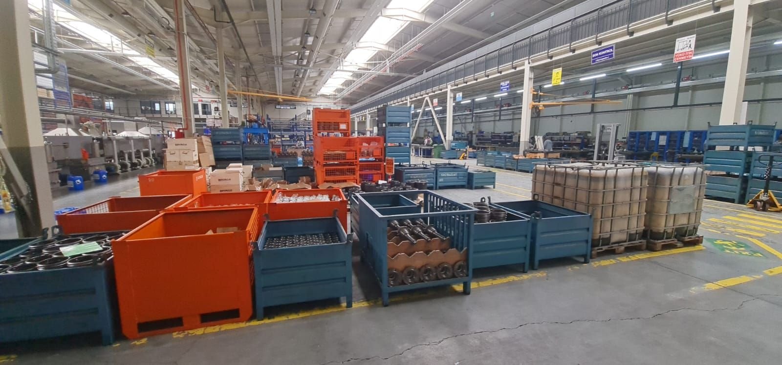 Manufactured metal parts in stillages on a factory floor awaiting collection